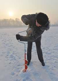 Александр Герасименко с помощью ледобура проверяет толщину льда на реке Абакан. 